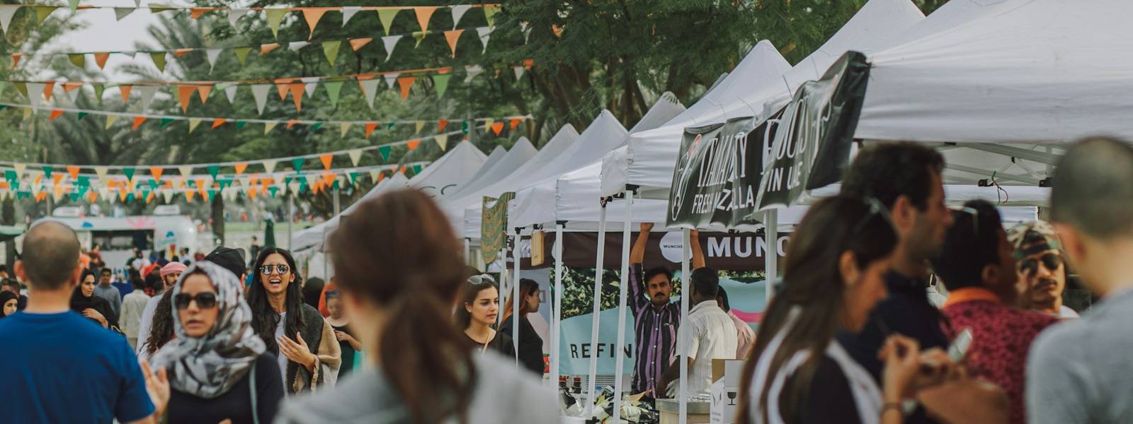 Crowd visiting white pop-up tents at an outdoor event