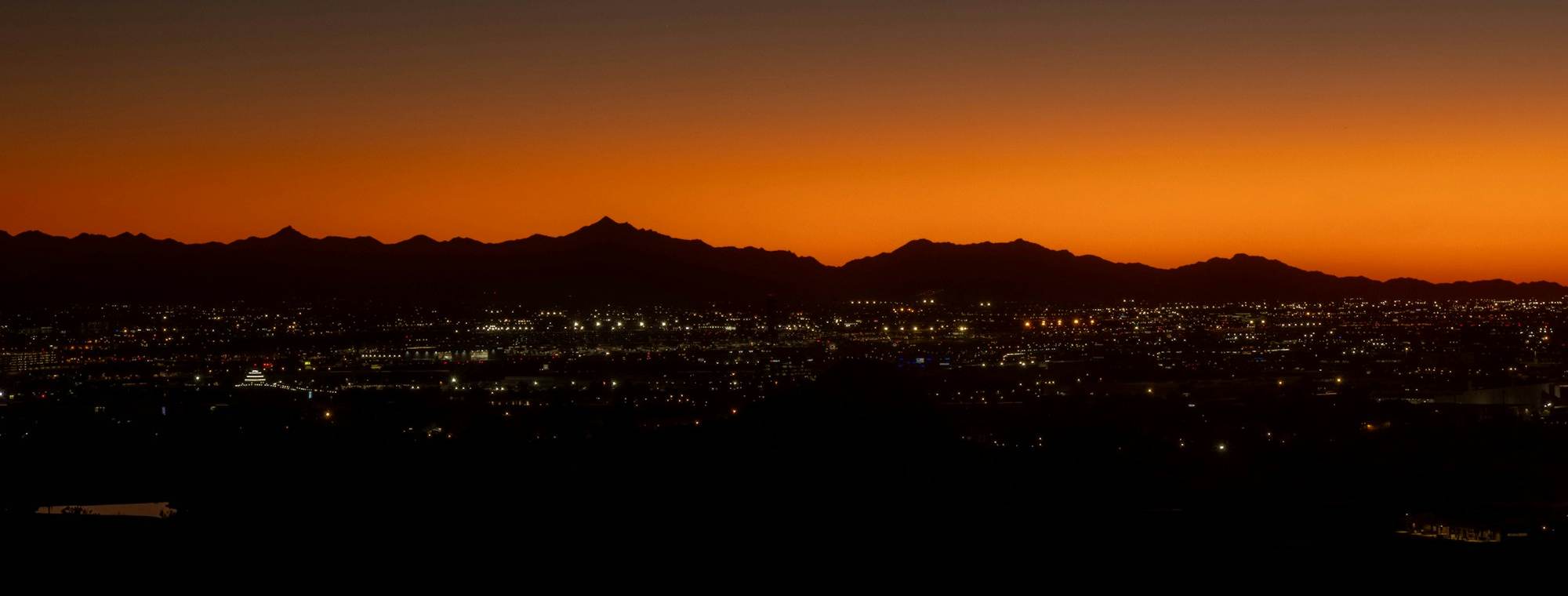 Phoenix city lights at sunset with desert mountains on the horizon