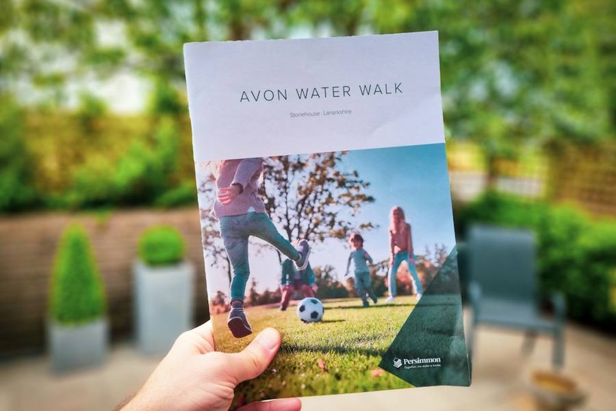 Person holding up a printed brochure outdoors